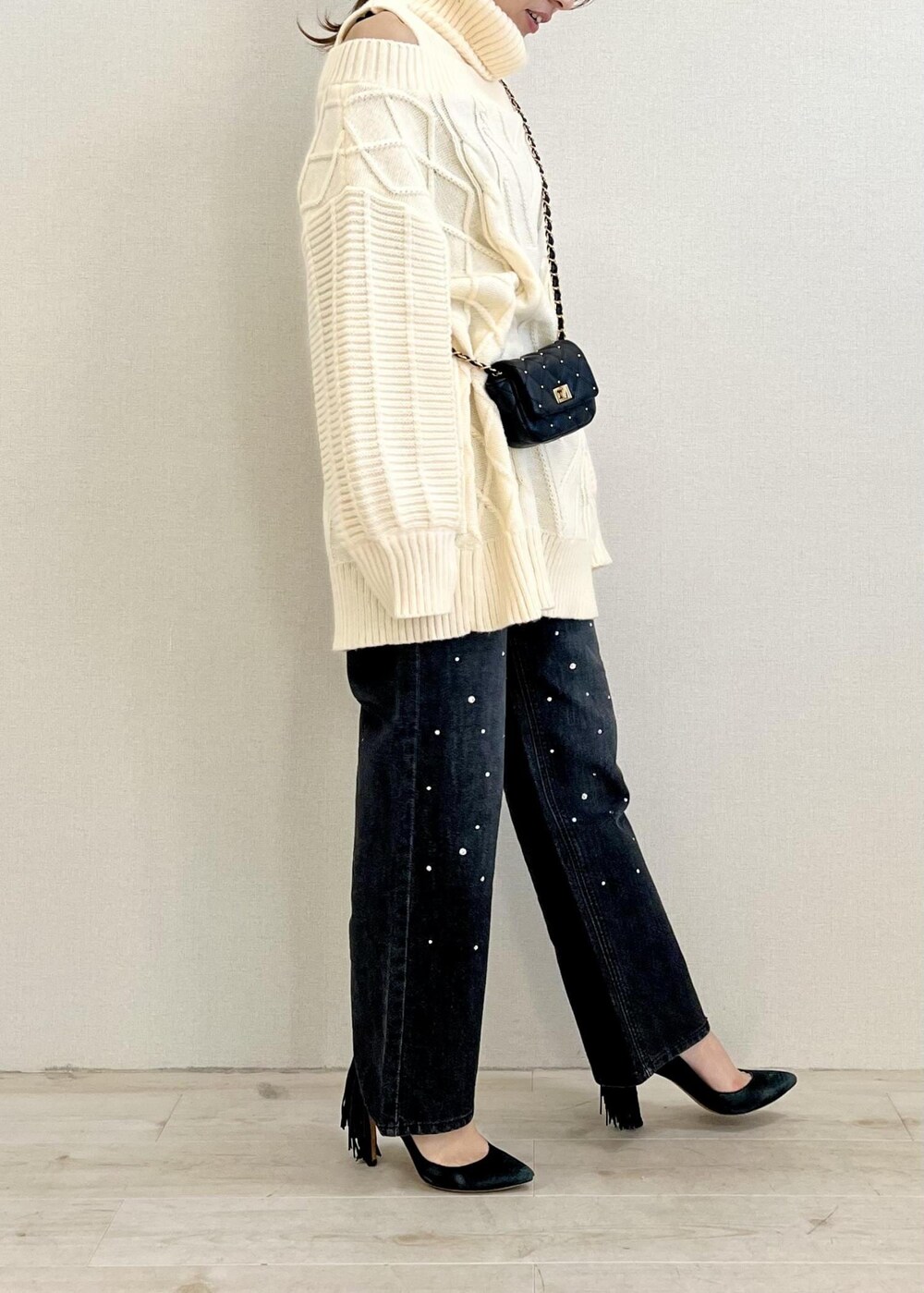 ブラック系のデニムパンツ、ホワイト系のワンピース、ブラック系のショルダーバッグを着用したレディースの冬コーディネートの2枚目の写真