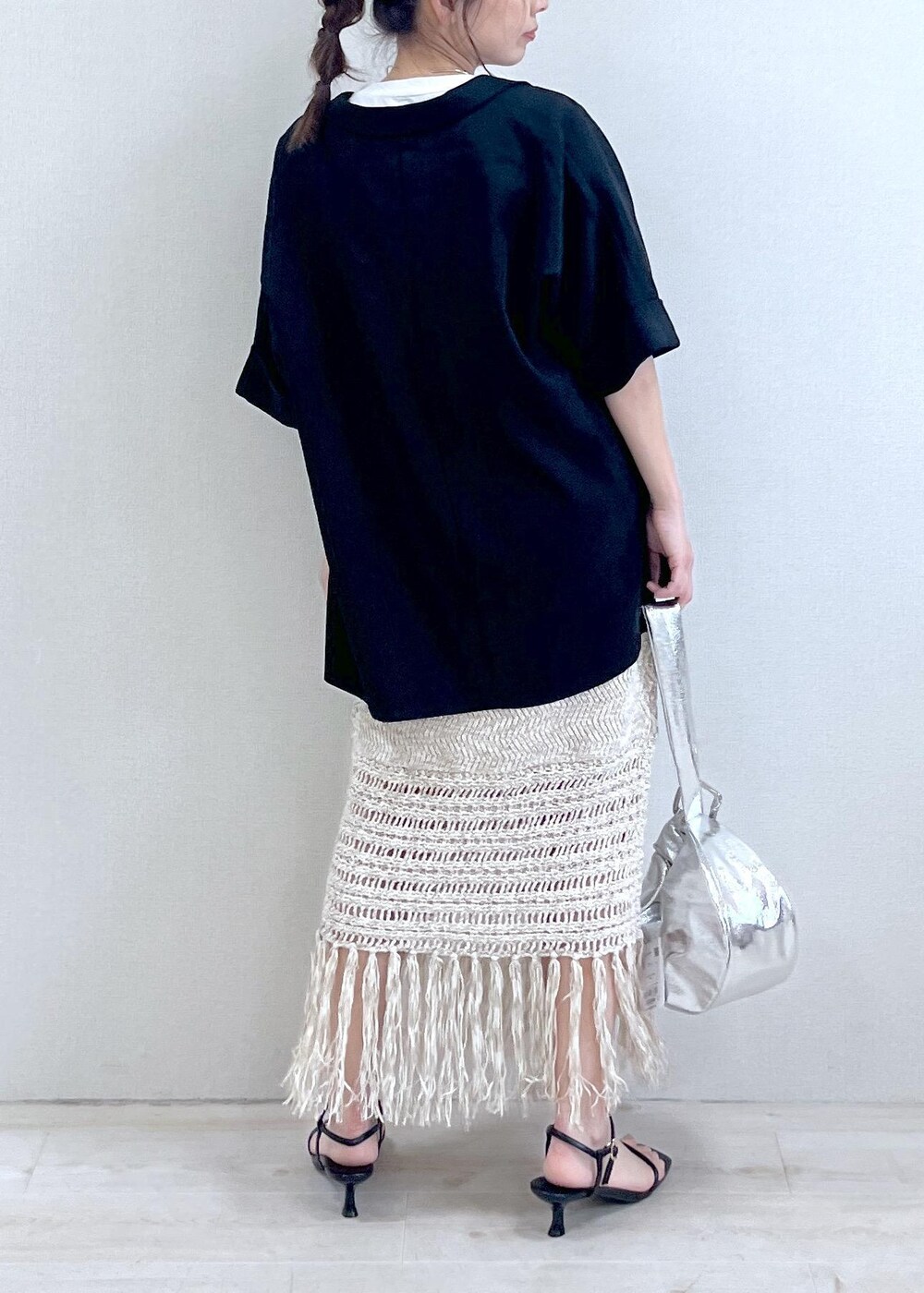 シルバー系のハンドバッグ、ベージュ系のスカート、ブラック系のサンダルを着用したレディースの春コーディネートの3枚目の写真