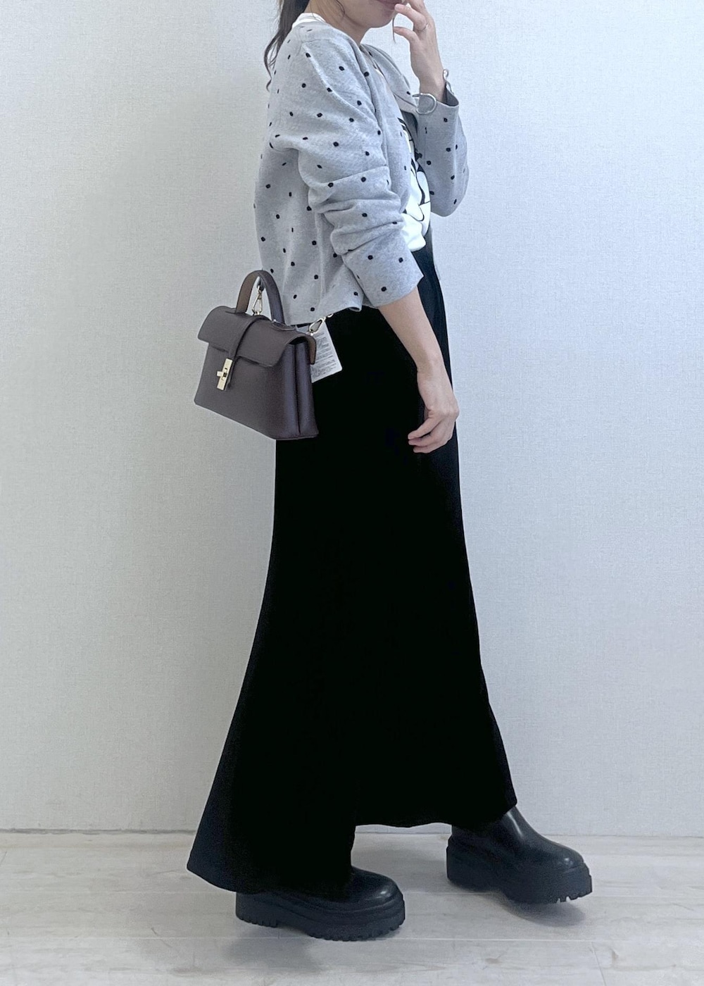 ブラウン系のショルダーバッグ、ブラック系のブーツ、ブラック系のスカートを着用したレディースの秋コーディネートの4枚目の写真