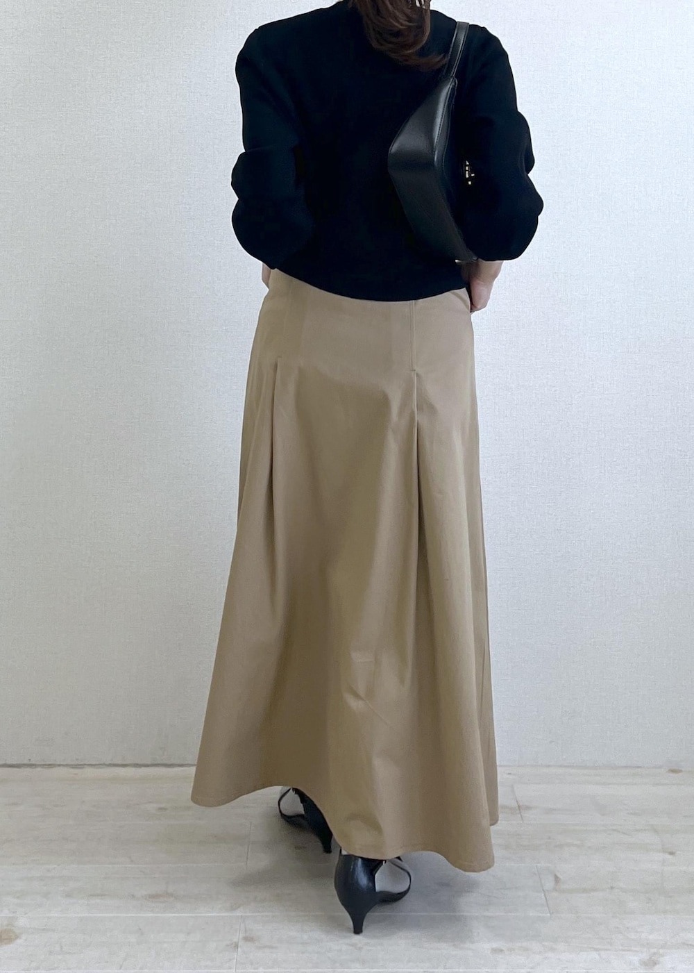 ブラック系のショルダーバッグ、ブラック系のカーディガン/ボレロ、ベージュ系のスカートを着用したレディースの春コーディネートの6枚目の写真