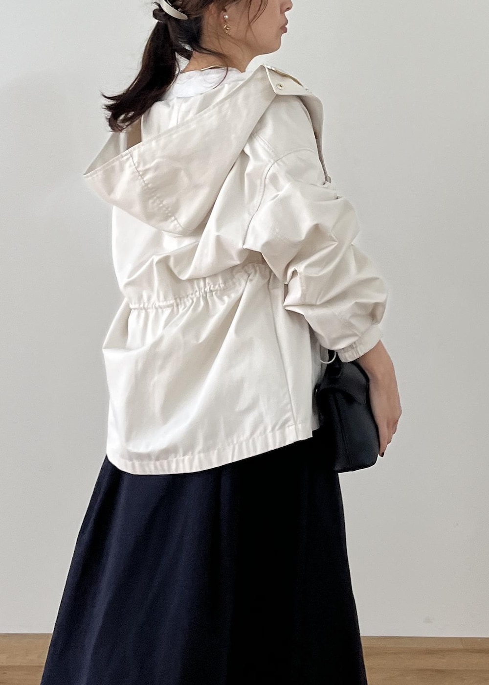 ブラック系のショルダーバッグ、ブラック系のパンプス、ホワイト系のナイロンジャケットを着用したレディースの冬コーディネートの4枚目の写真