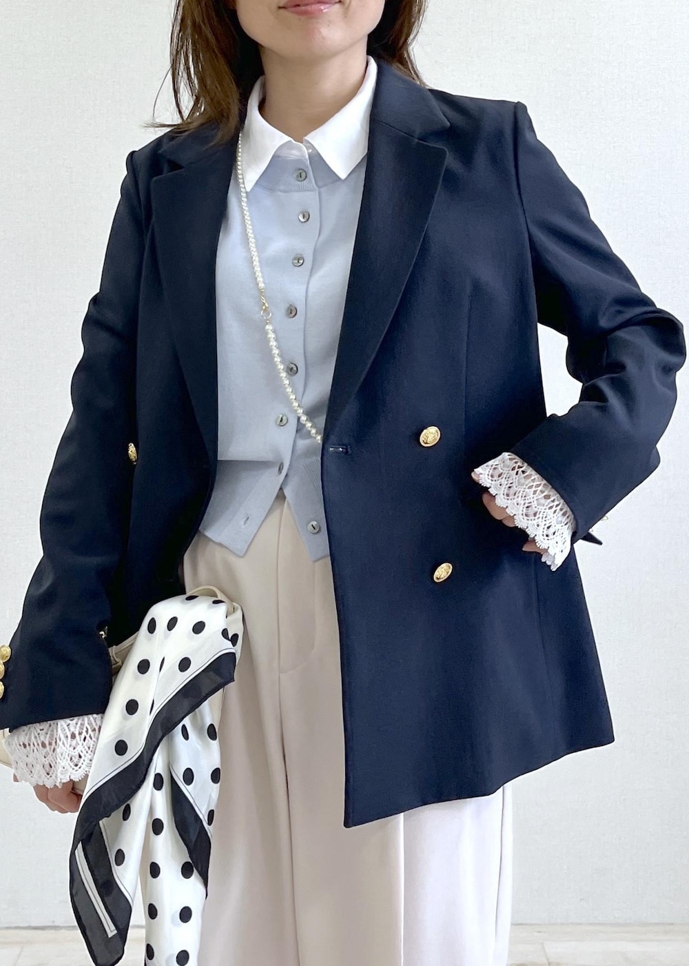 ホワイト系のショルダーバッグ、ブルー系のテーラードジャケット、ベージュ系のその他パンツを着用したレディースの春コーディネートの6枚目の写真
