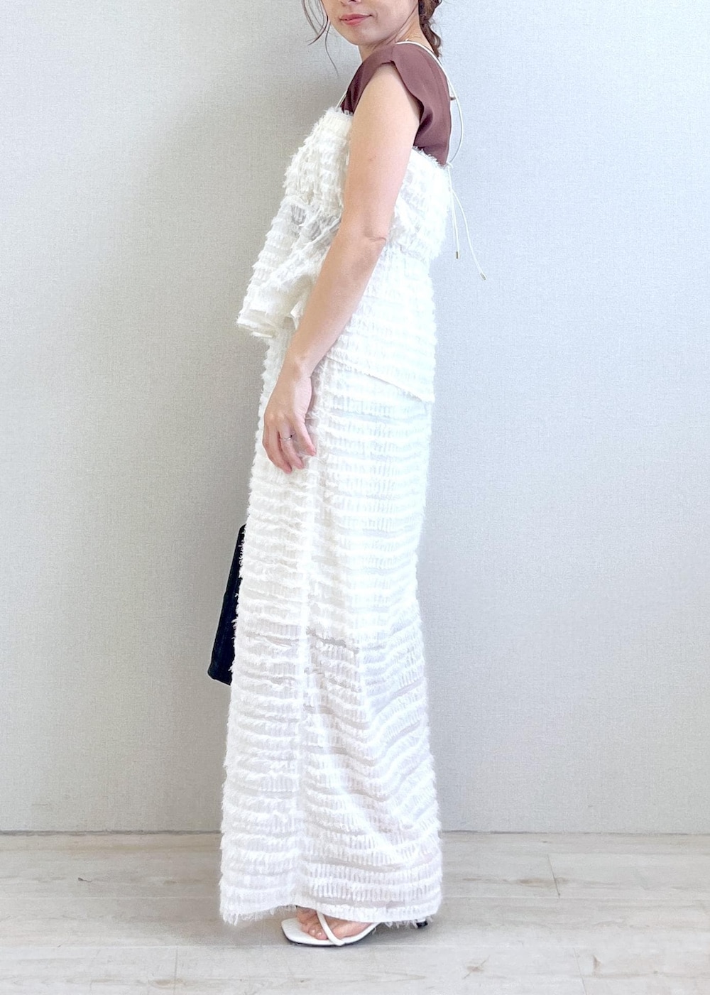 ブラック系のハンドバッグ、ホワイト系のサンダル、ブラウン系のニット/セーターを着用したレディースの春コーディネートの2枚目の写真