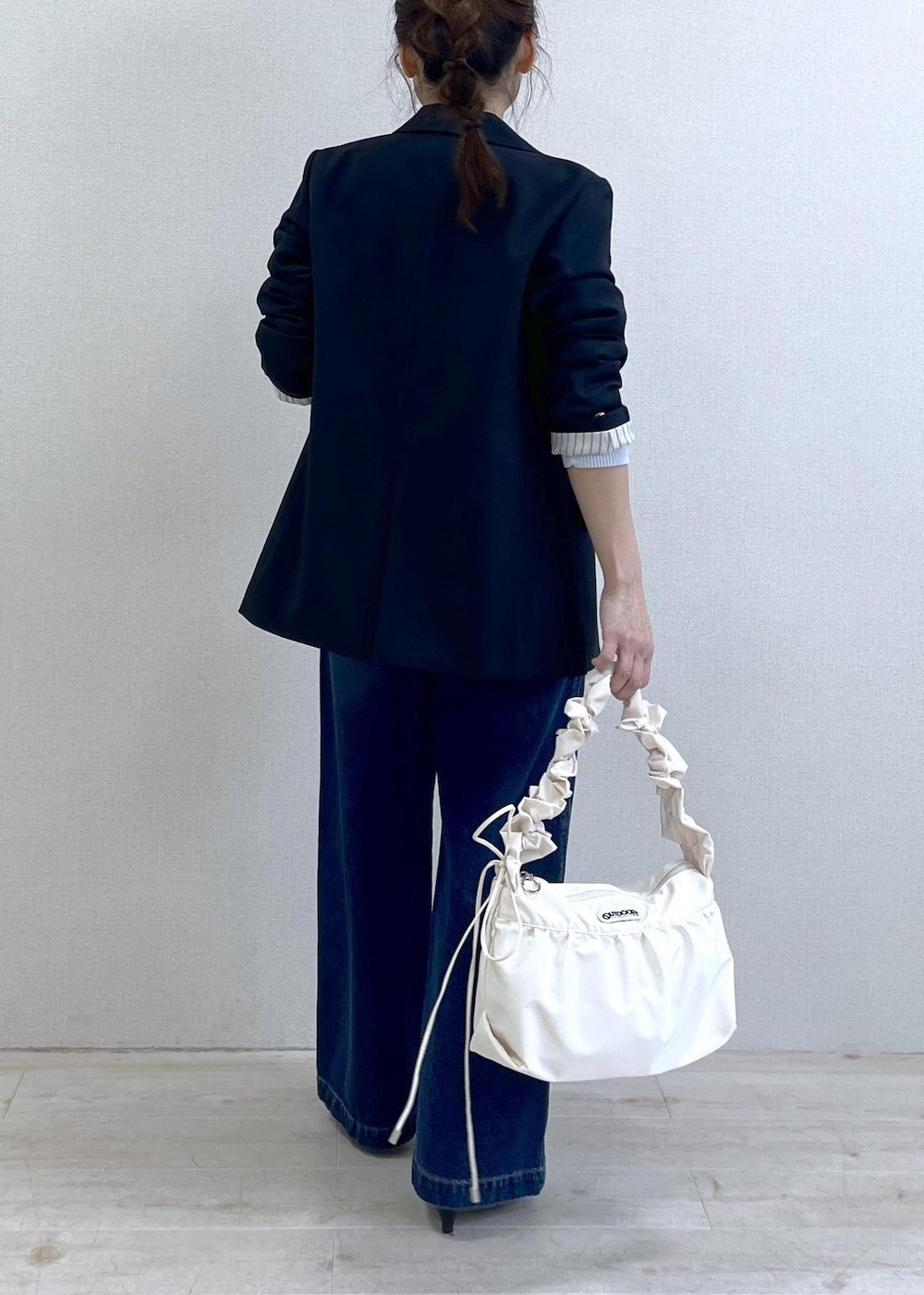 ブルー系のテーラードジャケット、ブルー系のデニムパンツ、ホワイト系のショルダーバッグを着用したレディースの冬コーディネートの4枚目の写真