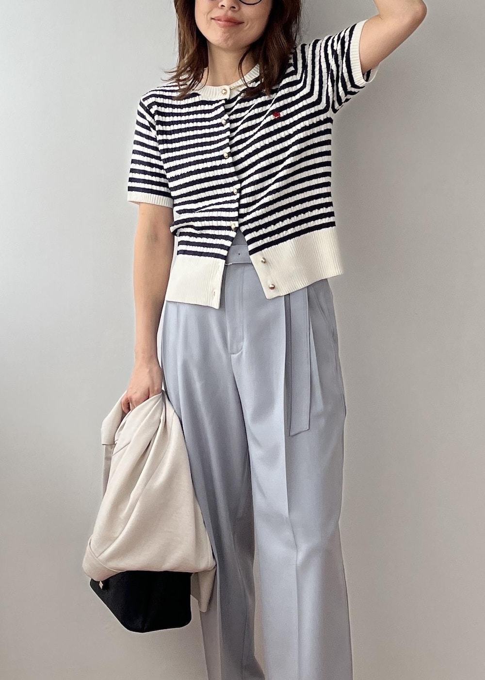 ブラック系のショルダーバッグ、ホワイト系のパンプス、ブルー系のその他パンツを着用したレディースの春コーディネートの9枚目の写真