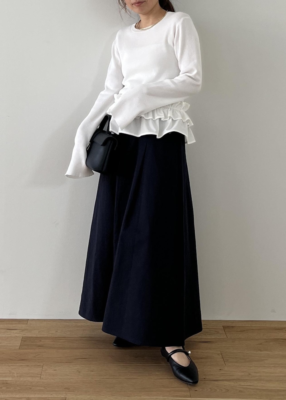 ブラック系のショルダーバッグ、ブラック系のパンプス、ホワイト系のナイロンジャケットを着用したレディースの冬コーディネートの7枚目の写真