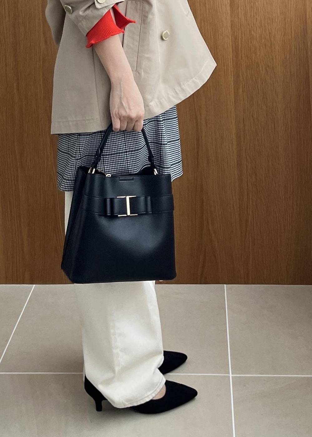 ブラック系のショルダーバッグ、ベージュ系のトレンチコート、ホワイト系のデニムパンツを着用したレディースの秋コーディネートの7枚目の写真