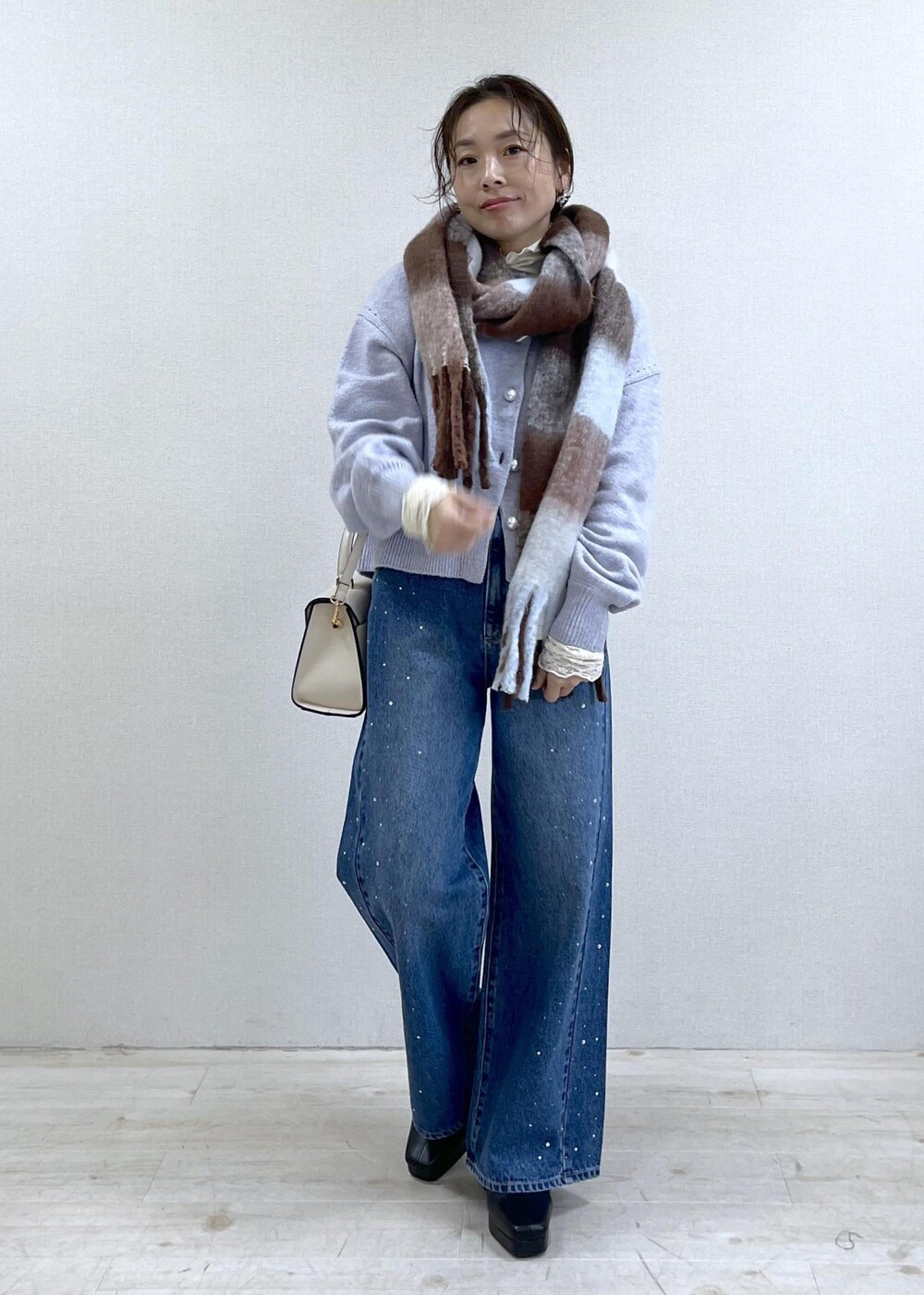 パープル系のカーディガン/ボレロ、ホワイト系のTシャツ/カットソー、ブラック系のブーツを着用したレディースの秋コーディネートの8枚目の写真