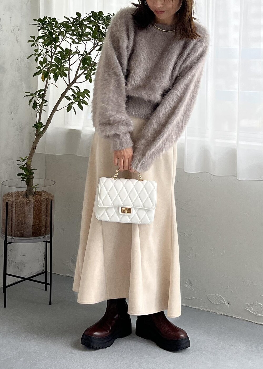 ブラウン系のブーツ、ホワイト系のスカート、ベージュ系のニット/セーターを着用したレディースの秋コーディネートの3枚目の写真