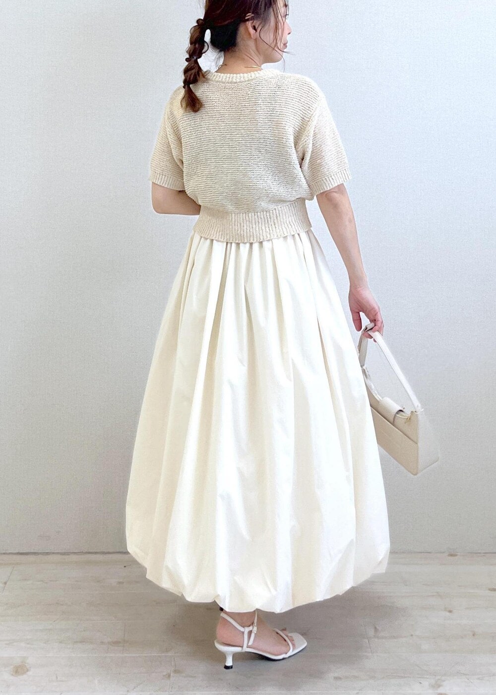 ホワイト系のハンドバッグ、ホワイト系のサンダル、ホワイト系のニット/セーターを着用したレディースの夏コーディネートの3枚目の写真