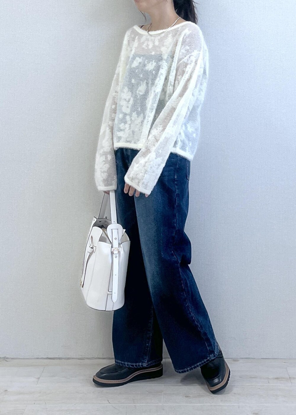 ブラック系のローファー、ホワイト系のニット/セーター、ブルー系のデニムパンツを着用したレディースの秋コーディネートの3枚目の写真