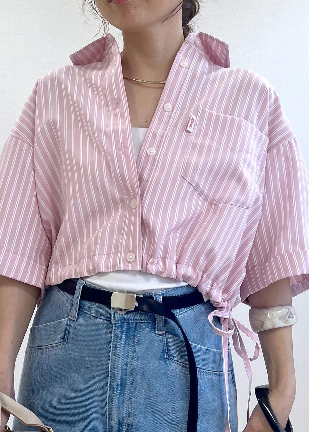 ブラック系のサンダル、ブルー系のデニムパンツ、ベージュ系のボストンバッグを着用したレディースの夏コーディネートの5枚目の写真