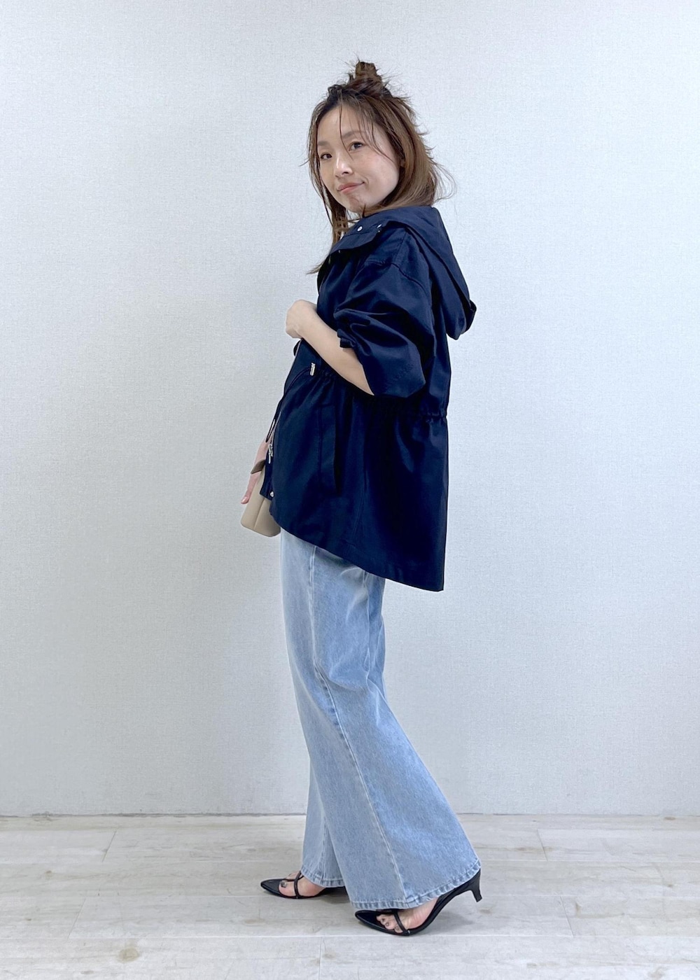 ベージュ系のショルダーバッグ、ブルー系のナイロンジャケット、ブラック系のキャミソールを着用したレディースの春コーディネートの3枚目の写真