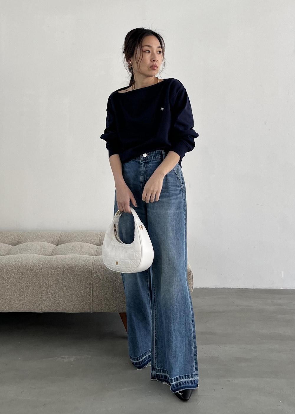 ホワイト系のハンドバッグ、ブラック系のパンプス、ブルー系のデニムパンツを着用したレディースの冬コーディネートの10枚目の写真