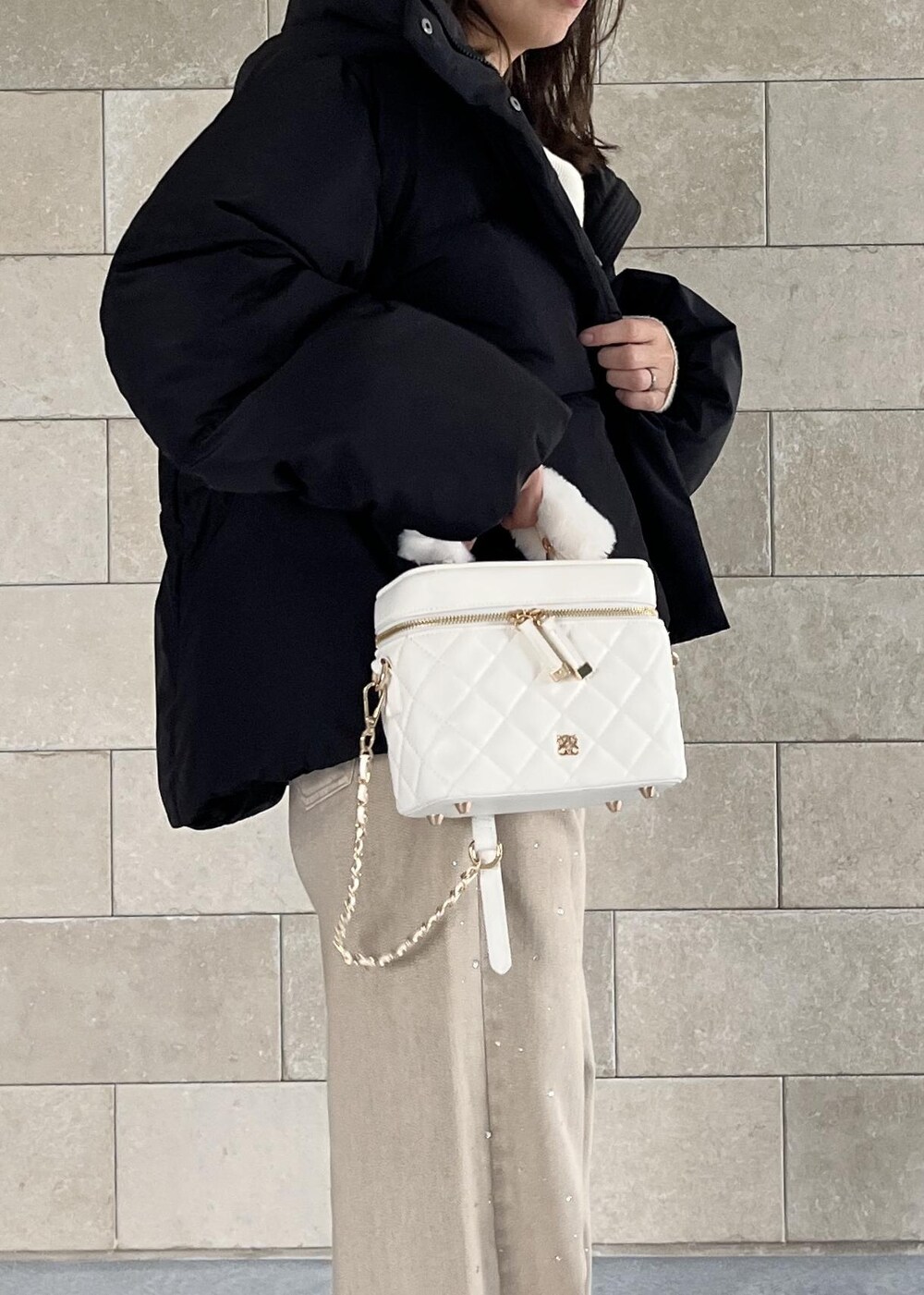 ブラック系のダウンジャケット/コート、ベージュ系のブーツ、ホワイト系のハンドバッグを着用したレディースの秋コーディネートの3枚目の写真