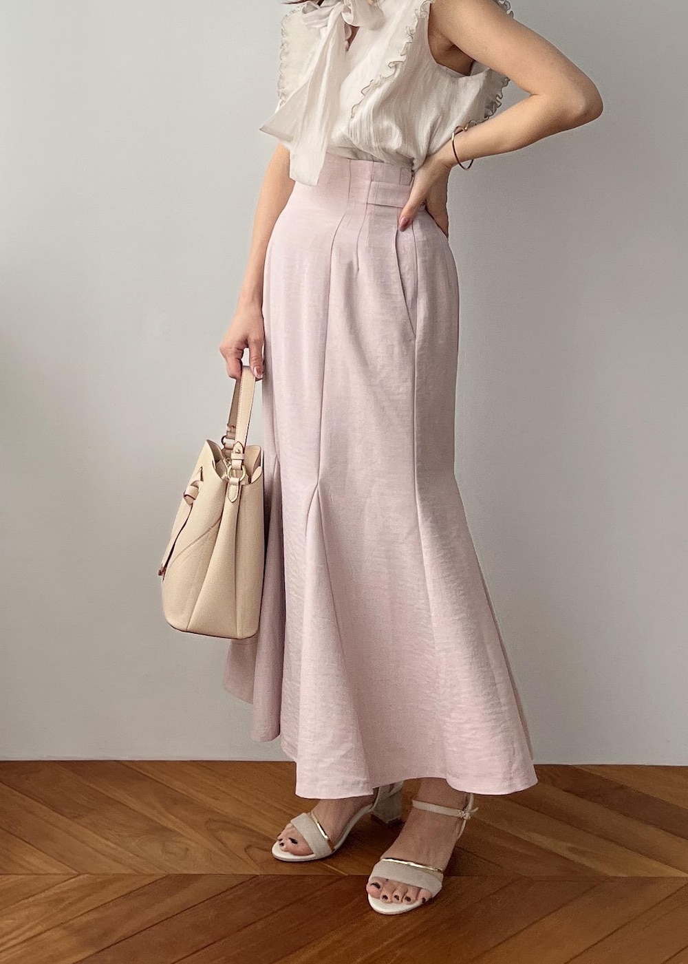 ベージュ系のショルダーバッグ、ピンク系のスカート、ホワイト系のサンダルを着用したレディースの春コーディネートの2枚目の写真