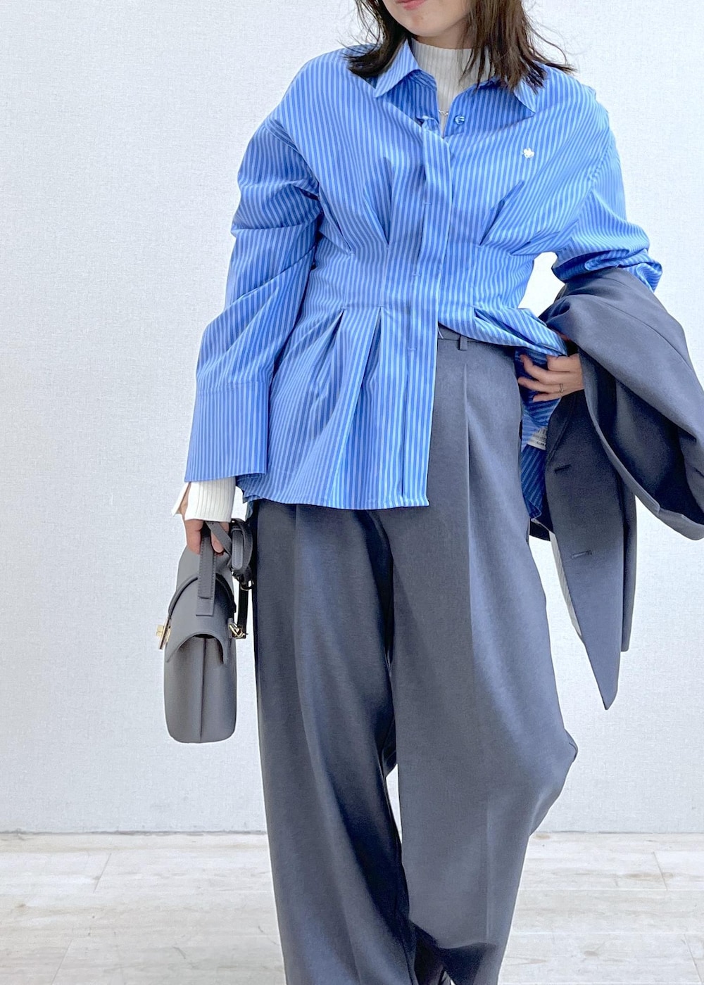 グレー系のショルダーバッグ、ブルー系のシャツ/ブラウス、ホワイト系のニット/セーターを着用したレディースの秋コーディネートの6枚目の写真