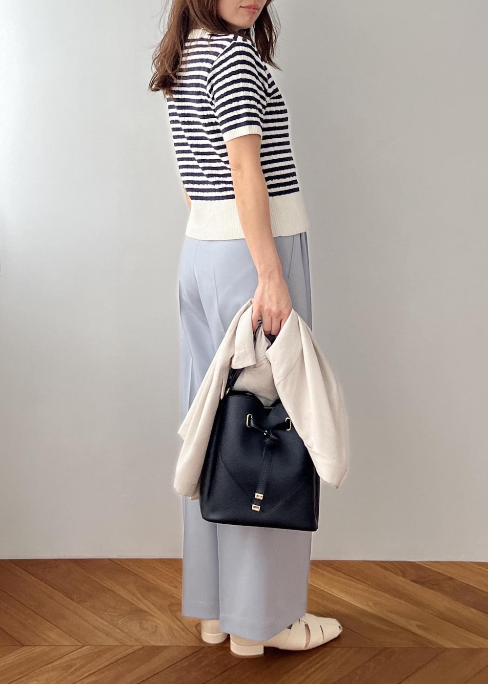 ブラック系のショルダーバッグ、ホワイト系のパンプス、ブルー系のその他パンツを着用したレディースの春コーディネートの6枚目の写真