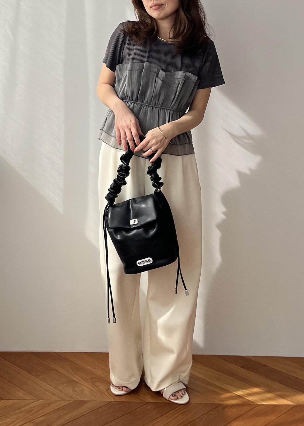 ホワイト系のスラックス、ブラック系のショルダーバッグ、ホワイト系のサンダルを着用したレディースの春コーディネートの9枚目の写真