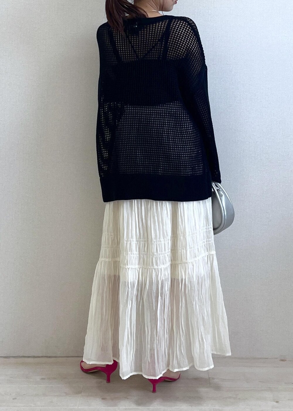 シルバー系のショルダーバッグ、ブラック系のニット/セーター、ホワイト系のスカートを着用したレディースの春コーディネートの2枚目の写真