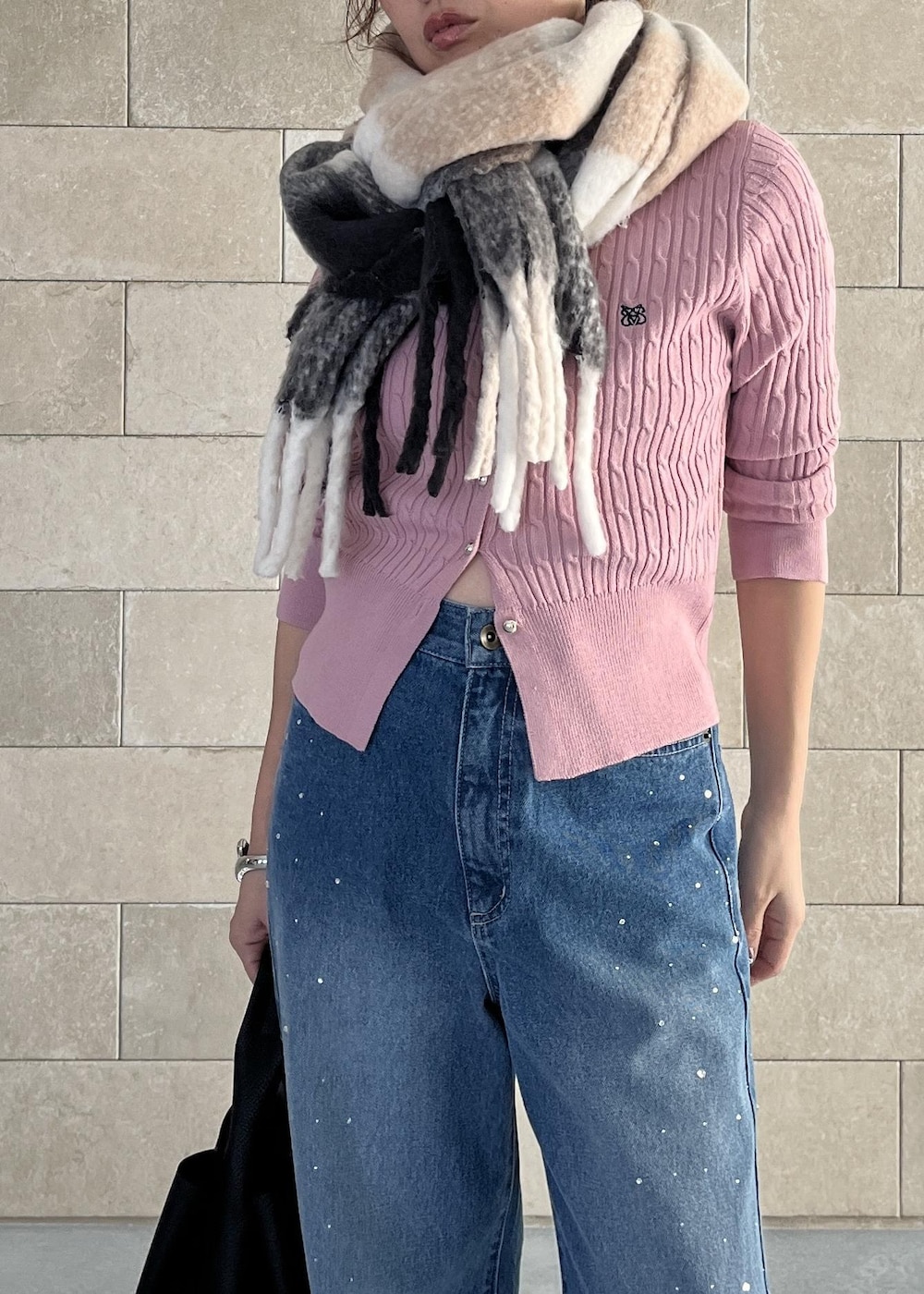 ブラック系のハンドバッグ、ピンク系のカーディガン/ボレロ、ブルー系のデニムパンツを着用したレディースの秋コーディネートの5枚目の写真