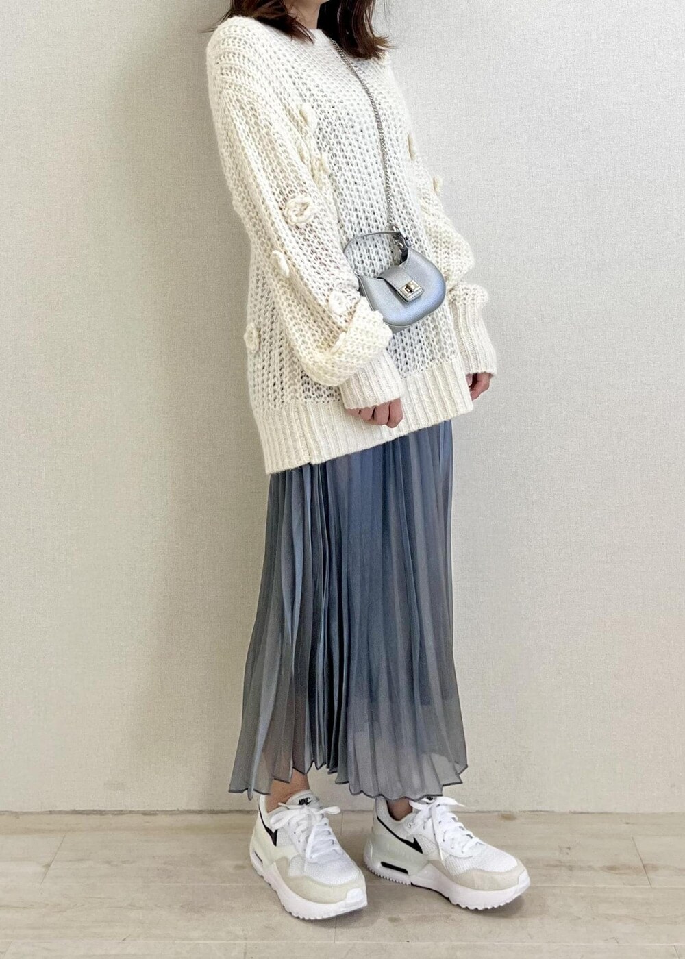 ホワイト系のニット/セーター、シルバー系のスカートを着用したレディースの冬コーディネートの3枚目の写真