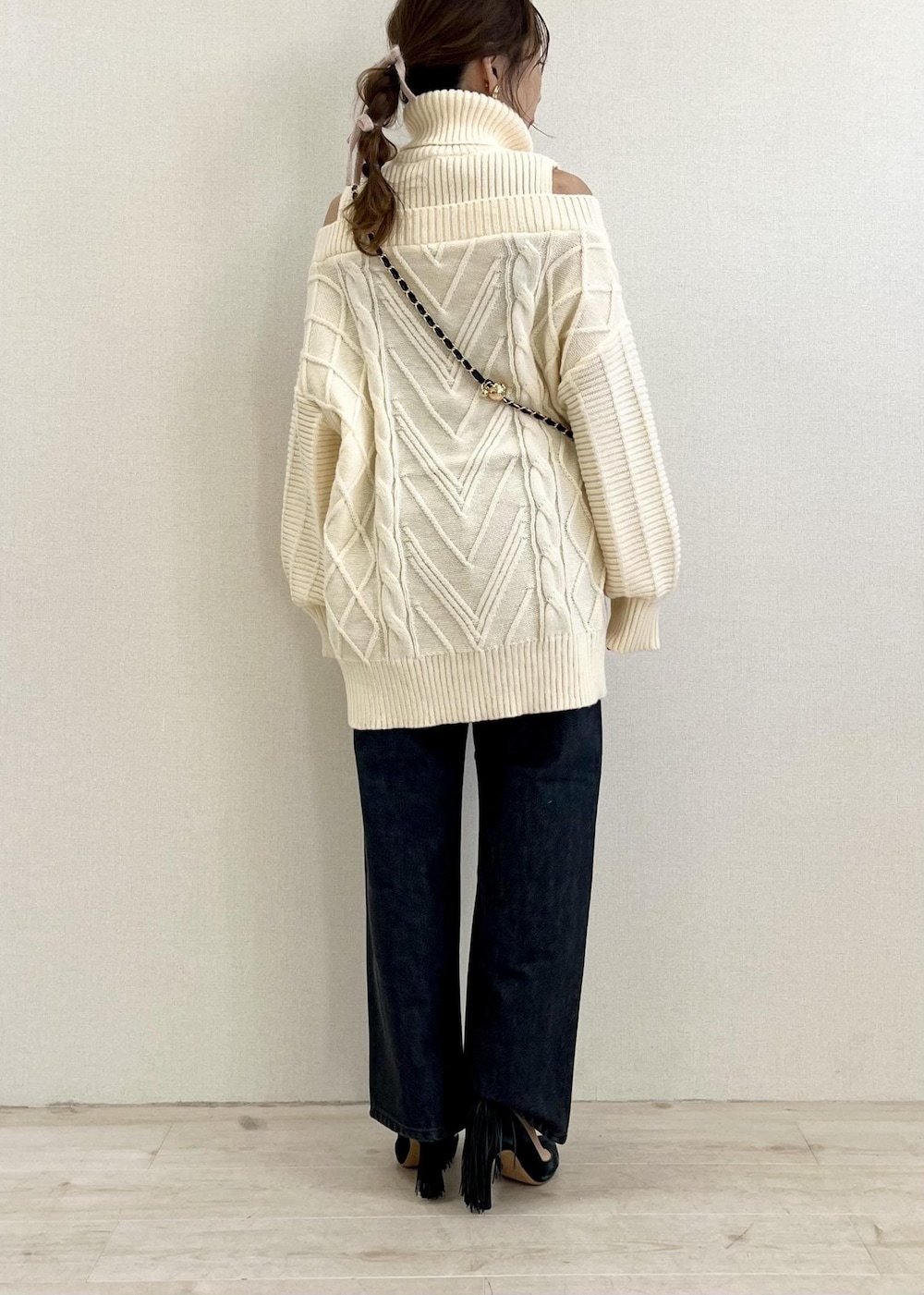 ブラック系のデニムパンツ、ホワイト系のワンピース、ブラック系のショルダーバッグを着用したレディースの冬コーディネートの3枚目の写真