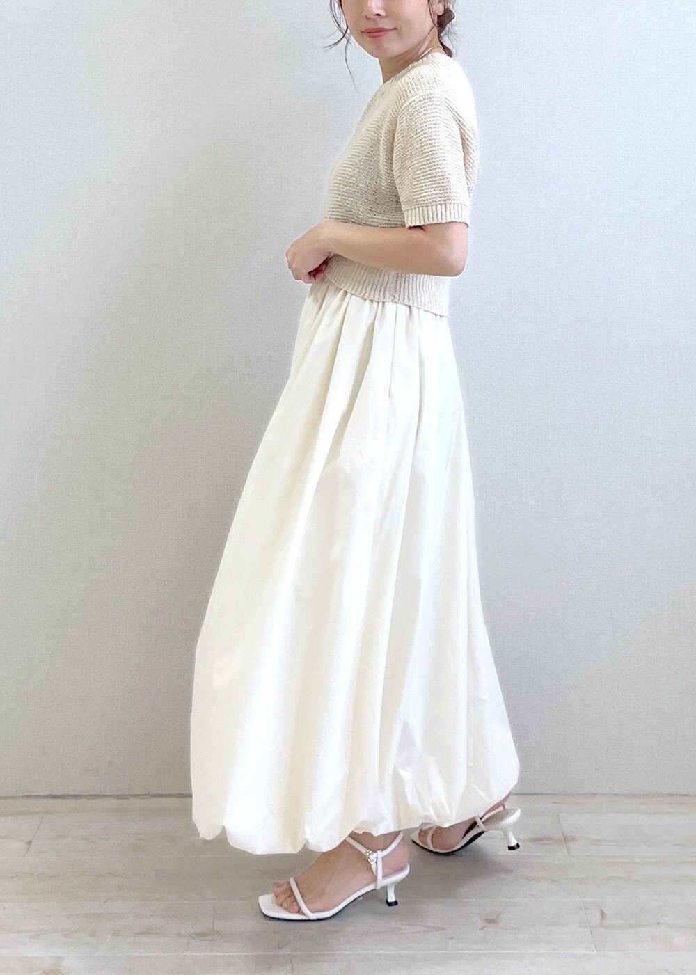 ホワイト系のハンドバッグ、ホワイト系のサンダル、ホワイト系のニット/セーターを着用したレディースの夏コーディネートの2枚目の写真