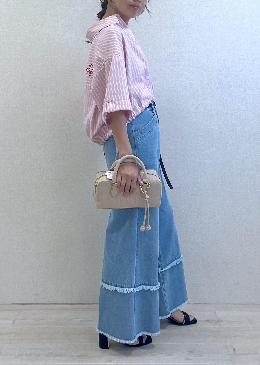 ブラック系のサンダル、ブルー系のデニムパンツ、ベージュ系のボストンバッグを着用したレディースの夏コーディネートの3枚目の写真