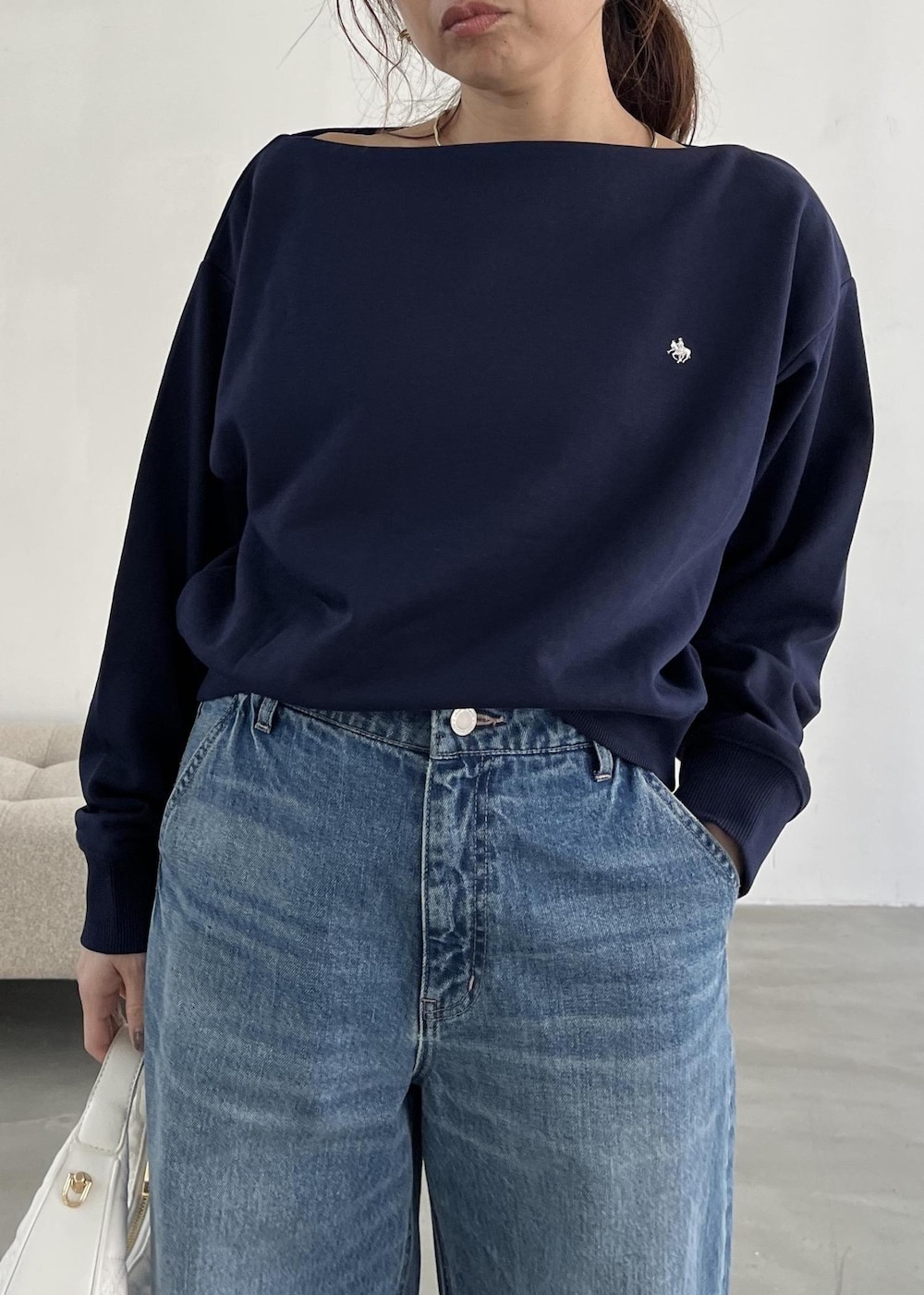 ホワイト系のハンドバッグ、ブラック系のパンプス、ブルー系のデニムパンツを着用したレディースの冬コーディネートの6枚目の写真