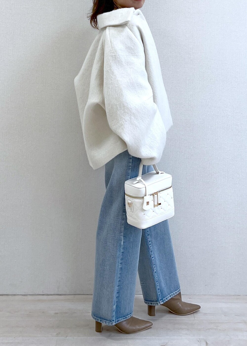 ベージュ系のブーツ、ホワイト系のその他アウター、ブルー系のデニムパンツを着用したレディースの秋コーディネートの3枚目の写真