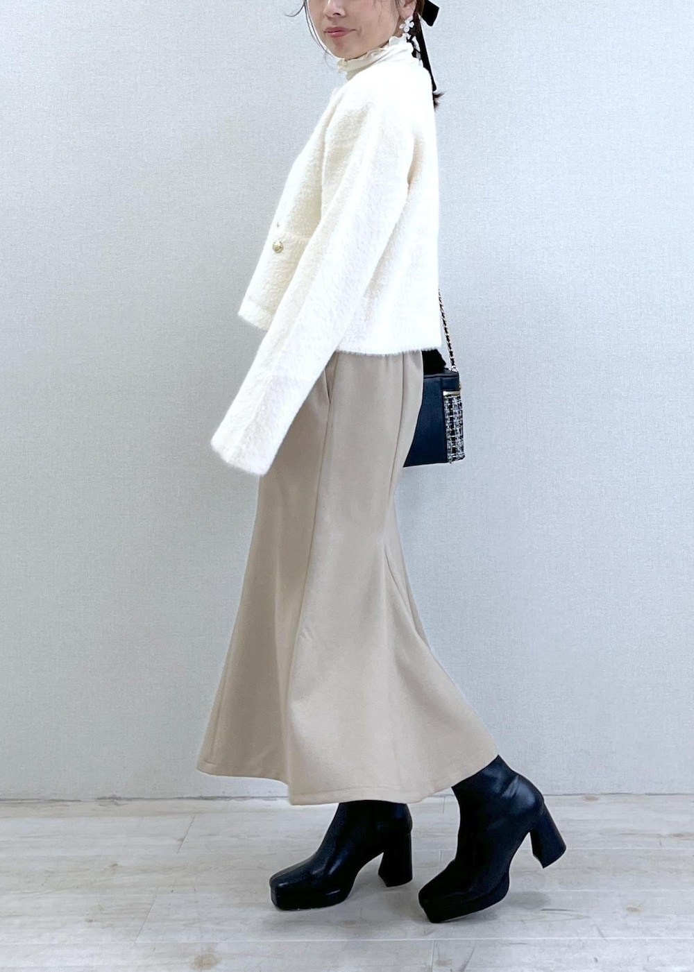 ベージュ系のスカート、ホワイト系のカーディガン/ボレロ、ホワイト系のTシャツ/カットソーを着用したレディースの秋コーディネートの2枚目の写真