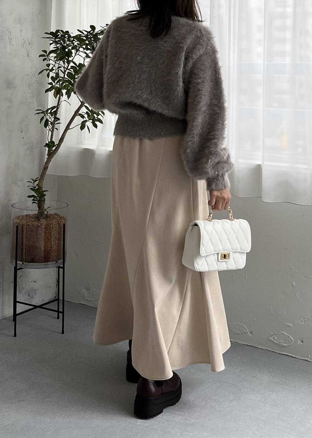 ブラウン系のブーツ、ホワイト系のスカート、ベージュ系のニット/セーターを着用したレディースの秋コーディネートの6枚目の写真