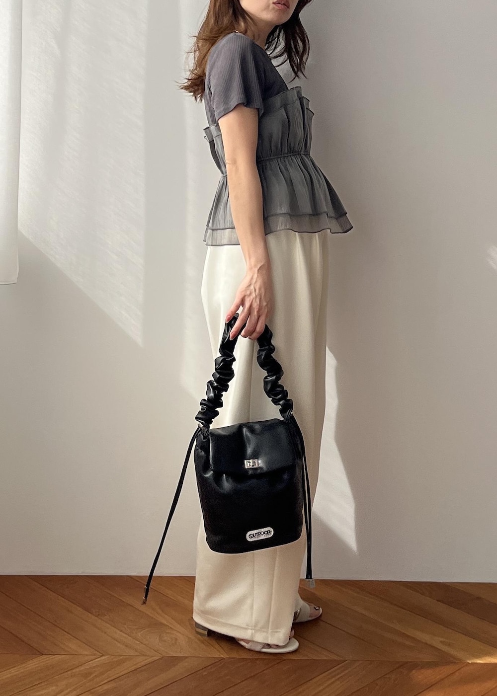 ホワイト系のスラックス、ブラック系のショルダーバッグ、ホワイト系のサンダルを着用したレディースの春コーディネートの10枚目の写真