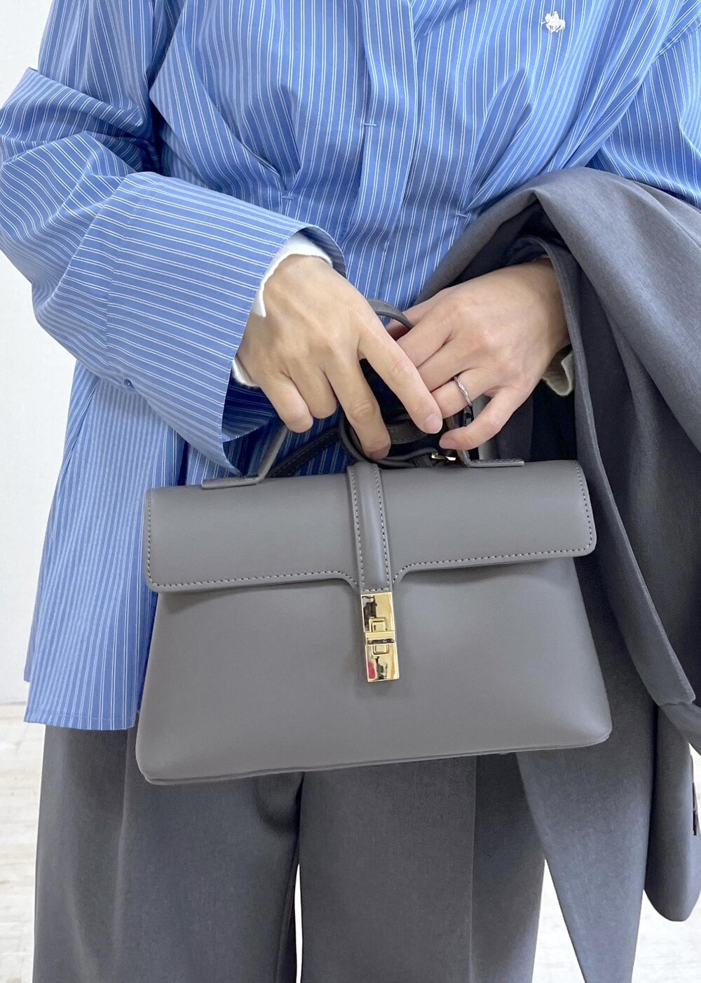 グレー系のショルダーバッグ、ブルー系のシャツ/ブラウス、ホワイト系のニット/セーターを着用したレディースの秋コーディネートの9枚目の写真