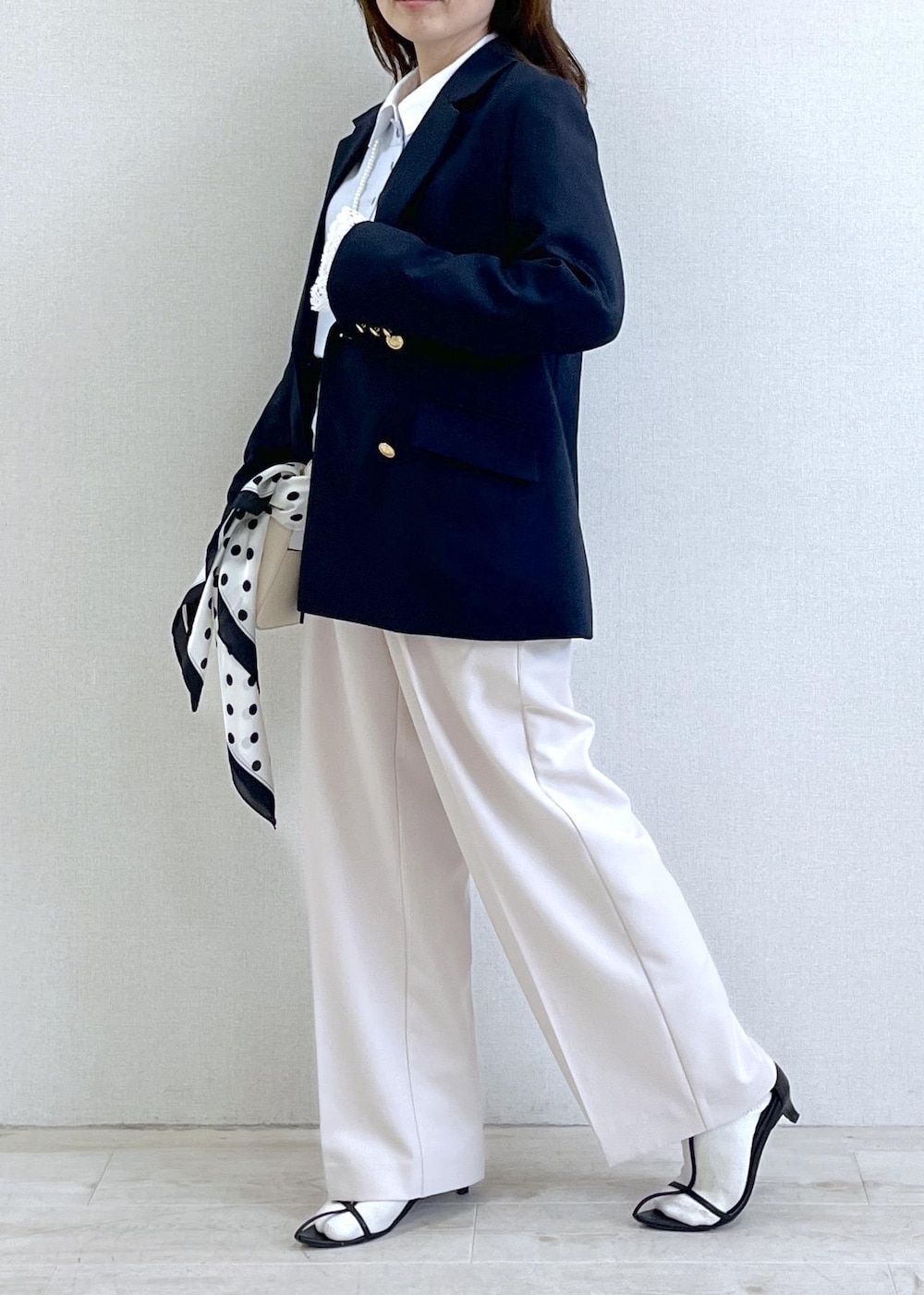 ホワイト系のショルダーバッグ、ブルー系のテーラードジャケット、ベージュ系のその他パンツを着用したレディースの春コーディネートの3枚目の写真