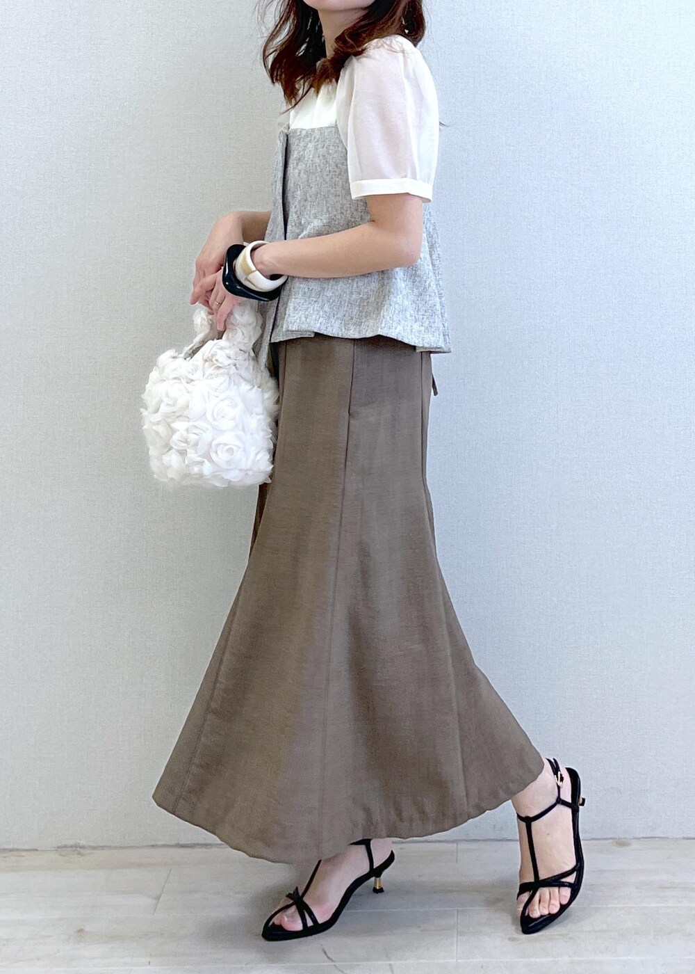 ブラック系のサンダル、ホワイト系のハンドバッグ、グリーン系のスカートを着用したレディースの春コーディネートの2枚目の写真