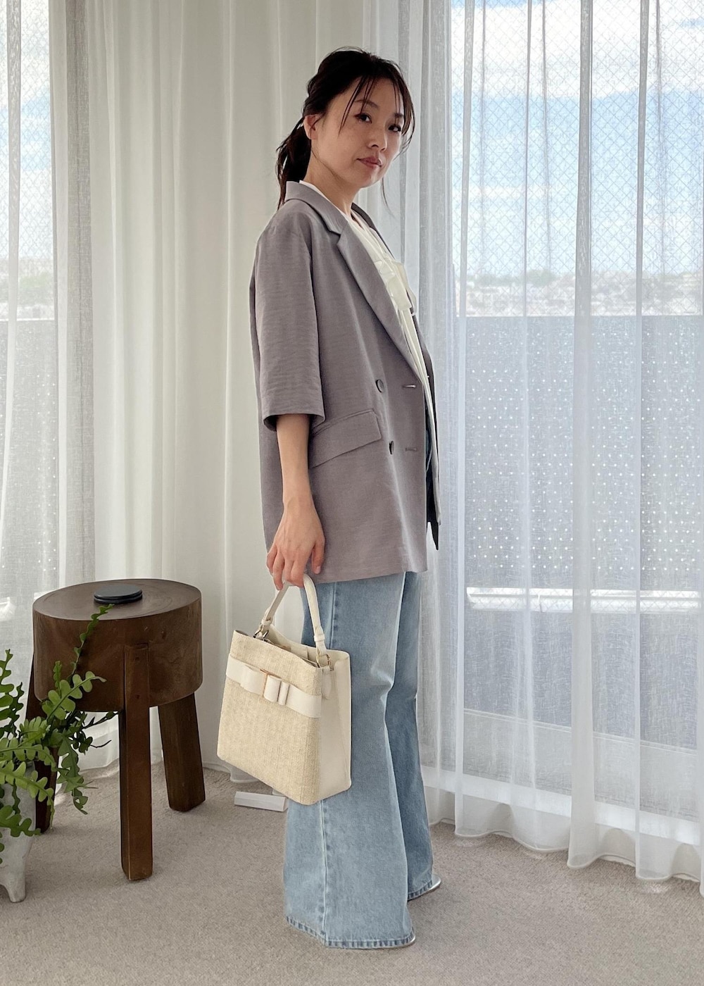 ブルー系のデニムパンツ、シルバー系のサンダル、グレー系のテーラードジャケットを着用したレディースの夏コーディネートの4枚目の写真