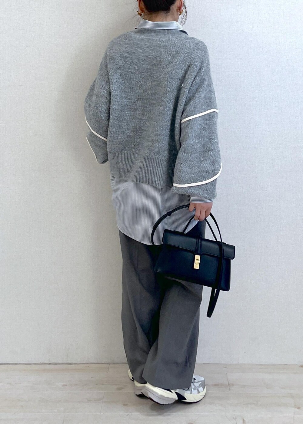 グレー系のニット/セーター、グレー系のスラックス、ブラック系のショルダーバッグを着用したレディースの冬コーディネートの4枚目の写真