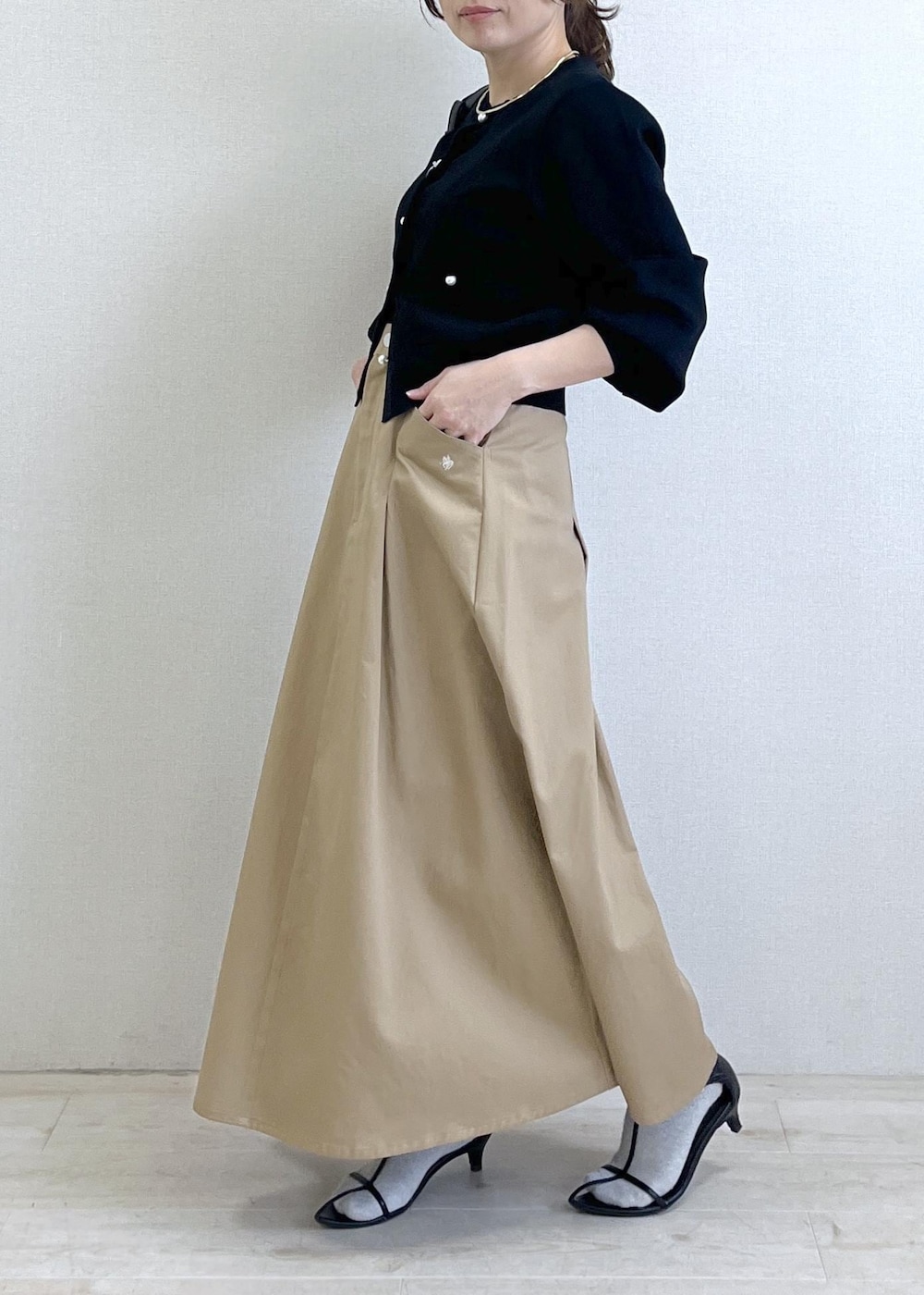 ブラック系のショルダーバッグ、ブラック系のカーディガン/ボレロ、ベージュ系のスカートを着用したレディースの春コーディネートの8枚目の写真