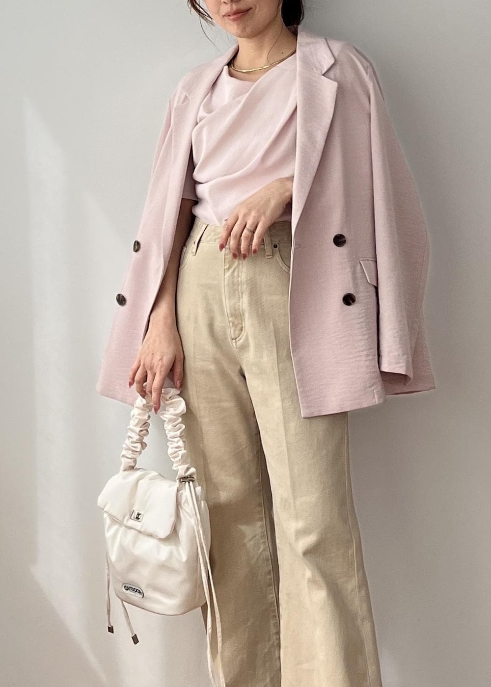 ホワイト系のショルダーバッグ、ピンク系のテーラードジャケット、ベージュ系のデニムパンツを着用したレディースの春コーディネートの7枚目の写真
