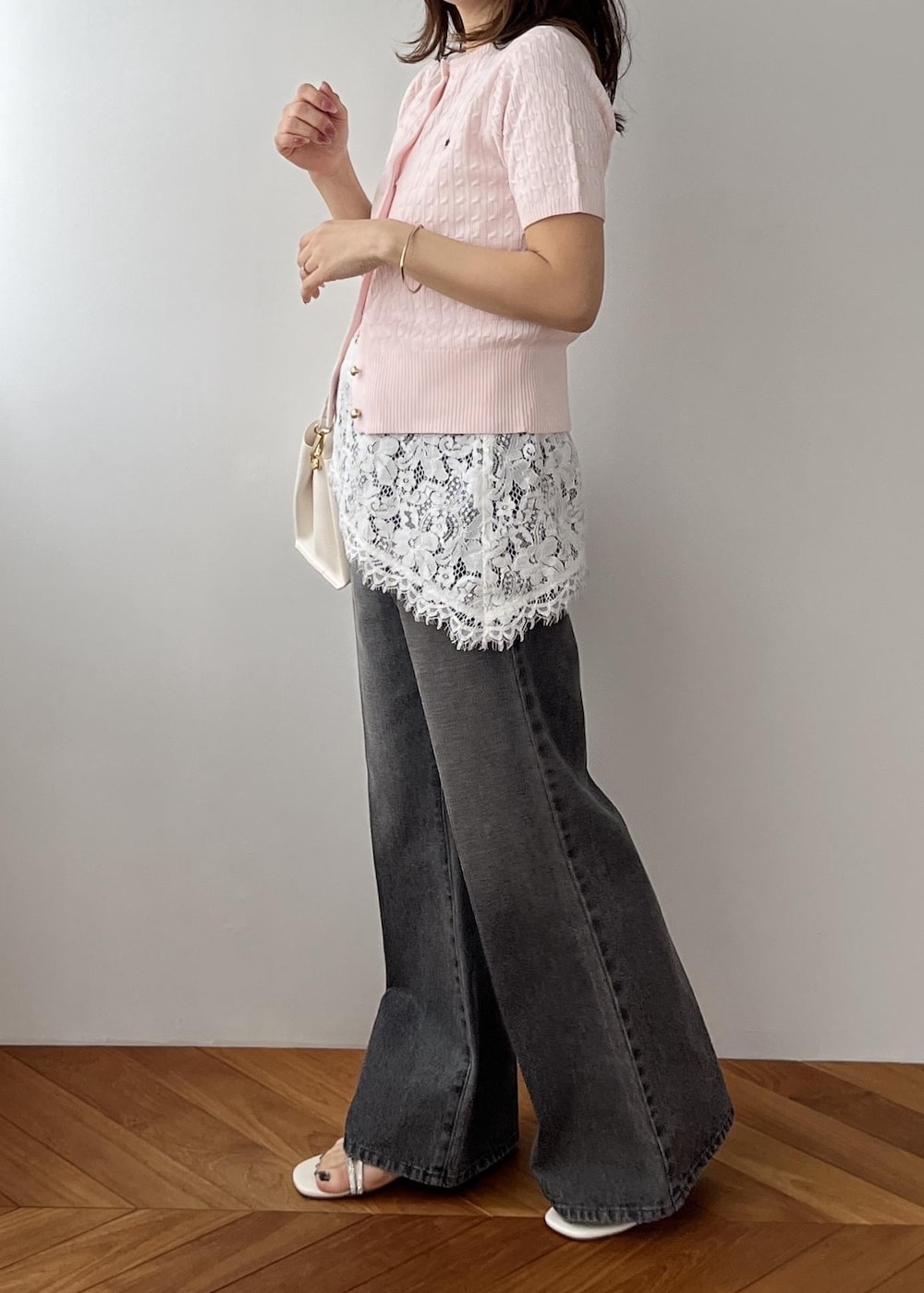 ホワイト系のキャミソール、ブラック系のデニムパンツ、ホワイト系のショルダーバッグを着用したレディースの春コーディネートの3枚目の写真