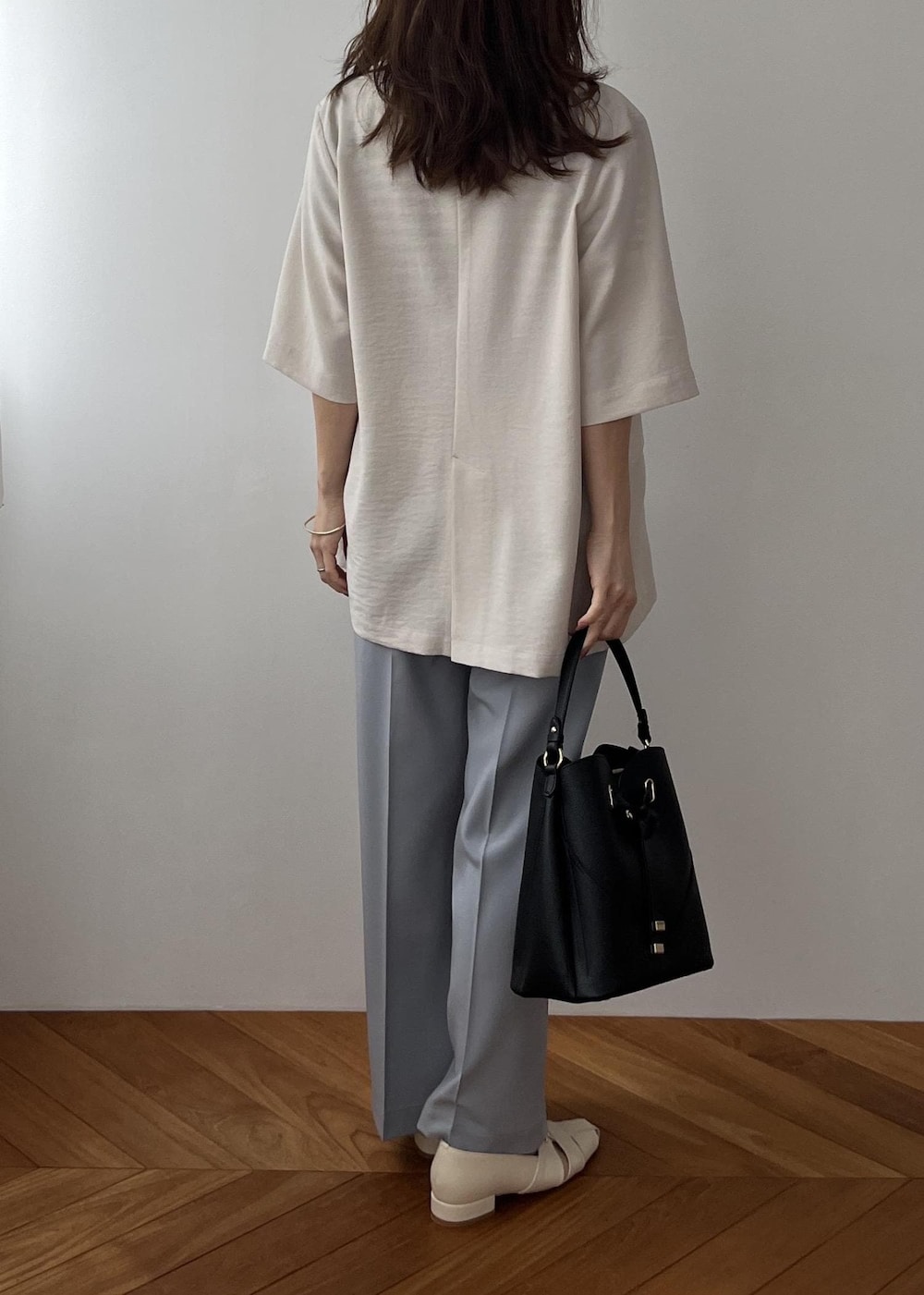 ブラック系のショルダーバッグ、ホワイト系のパンプス、ブルー系のその他パンツを着用したレディースの春コーディネートの4枚目の写真