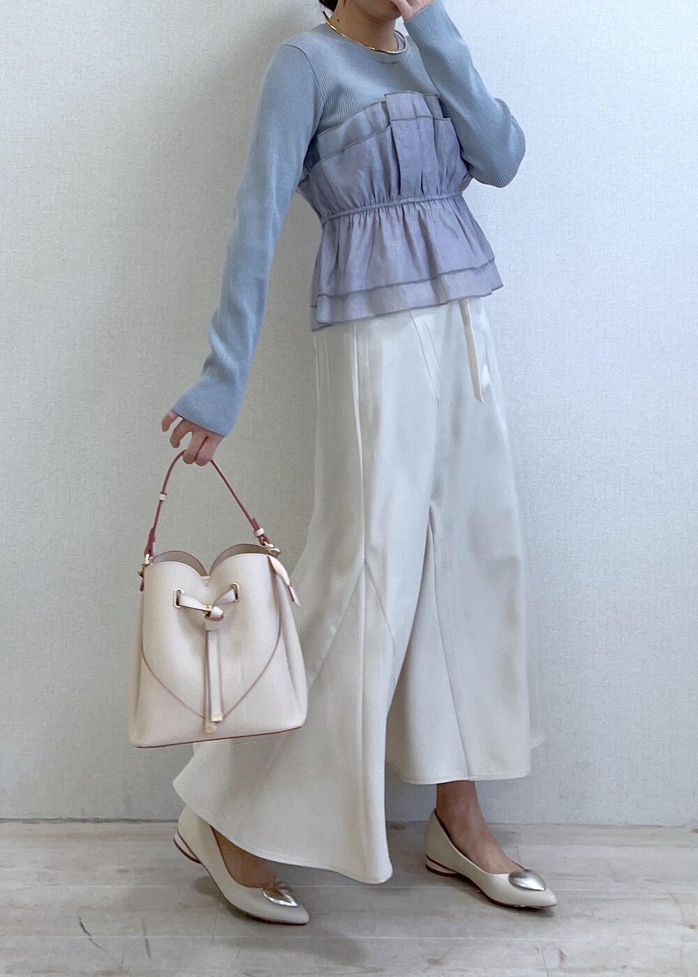 ベージュ系のショルダーバッグ、ホワイト系のバレエシューズ、ブルー系のニット/セーターを着用したレディースの春コーディネートの3枚目の写真