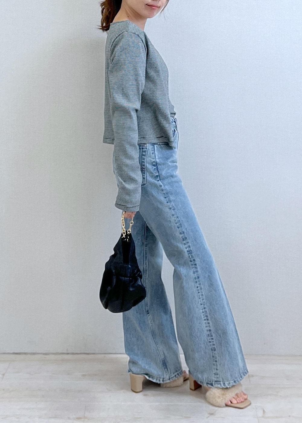 ベージュ系のドレスシューズ、ブラック系のアンサンブル、ブルー系のデニムパンツを着用したレディースの秋コーディネートの3枚目の写真