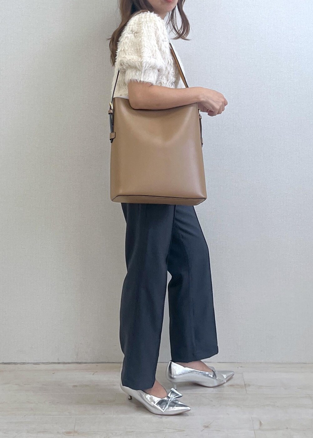 シルバー系のパンプス、イエロー系のショルダーバッグ、ホワイト系のニット/セーターを着用したレディースの秋コーディネートの3枚目の写真