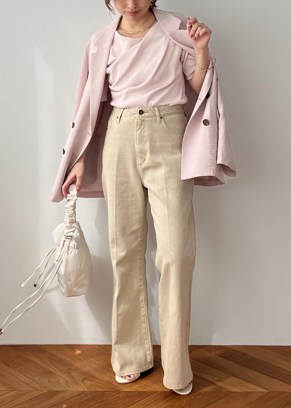 ホワイト系のショルダーバッグ、ピンク系のテーラードジャケット、ベージュ系のデニムパンツを着用したレディースの春コーディネートの6枚目の写真
