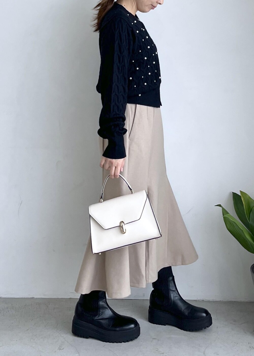 ブラック系のブーツ、ベージュ系のスカート、ブラック系のカーディガン/ボレロを着用したレディースの秋コーディネートの3枚目の写真