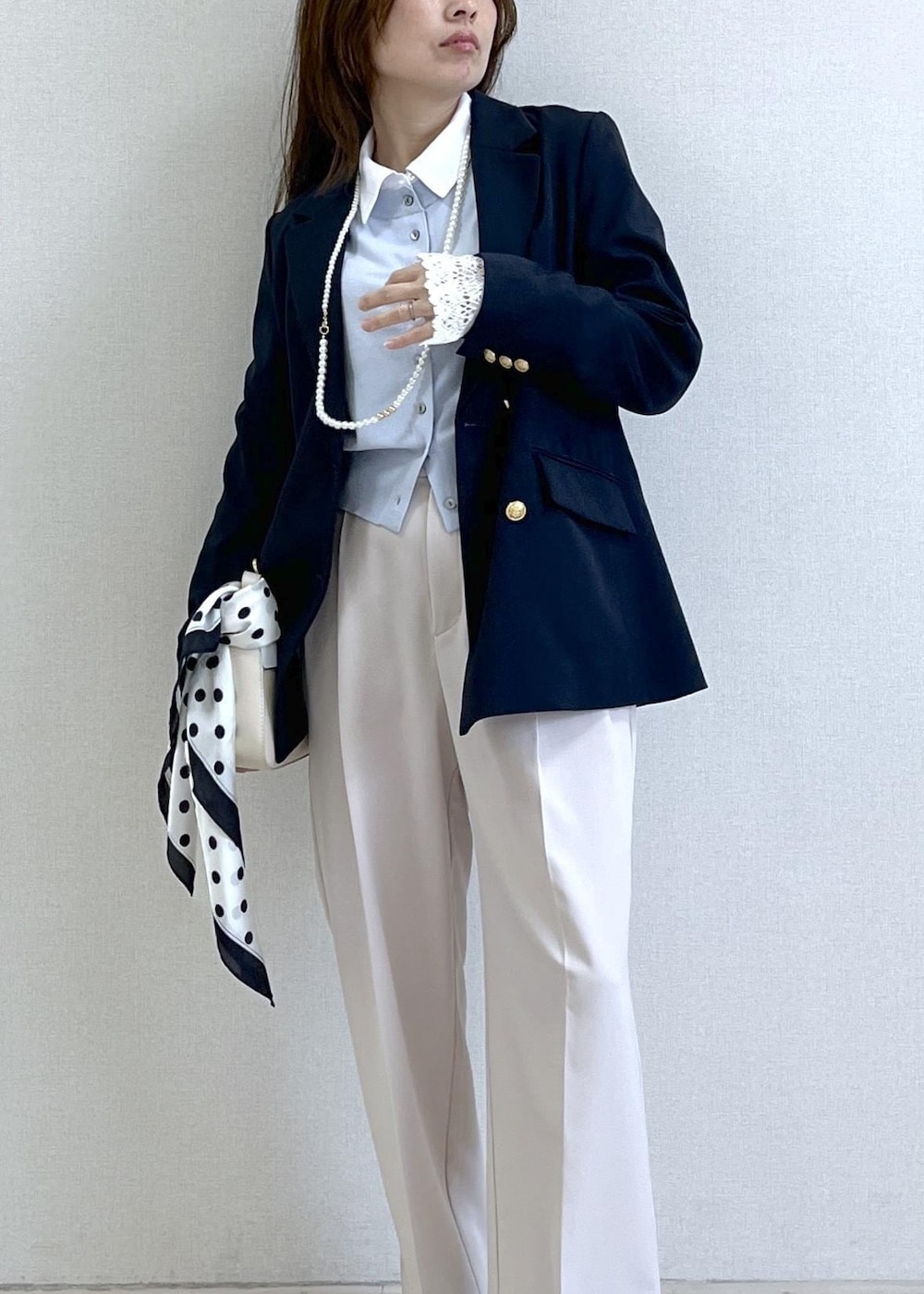 ホワイト系のショルダーバッグ、ブルー系のテーラードジャケット、ベージュ系のその他パンツを着用したレディースの春コーディネートの2枚目の写真