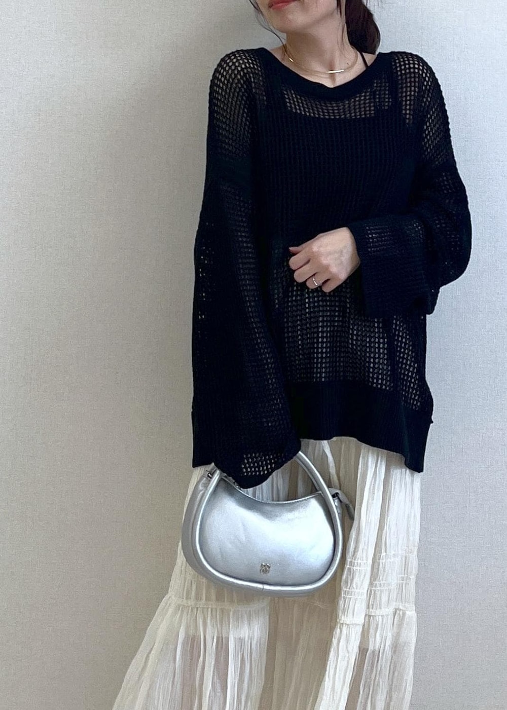 シルバー系のショルダーバッグ、ブラック系のニット/セーター、ホワイト系のスカートを着用したレディースの春コーディネートの3枚目の写真